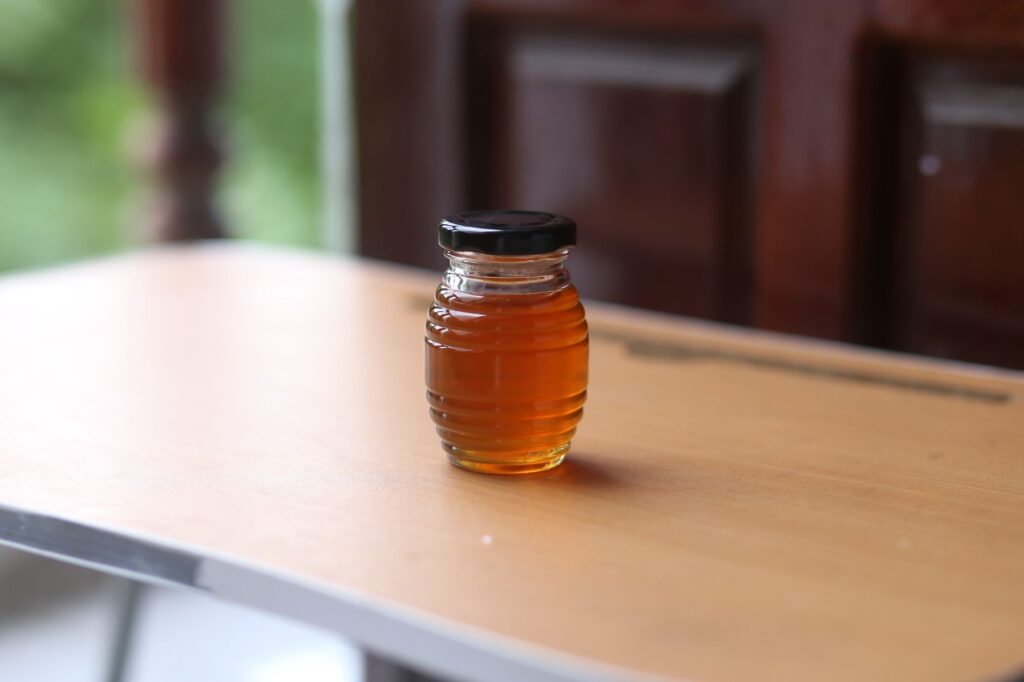 bocal de liquide ambré posé sur une table en bois près d'une porte