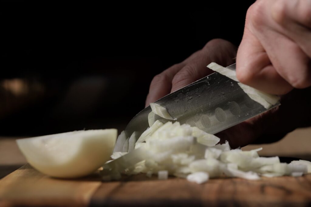 oignon émincé au couteau sur une planche à découper en bois